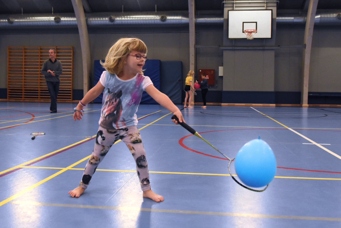 Billed af pige der spiller badminton med en ballon